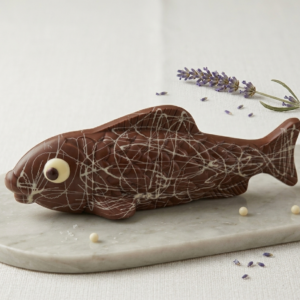 Long poisson en chocolat lait avec des rayures blanches posé sur une plaque de marbre.