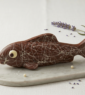 Long poisson en chocolat lait avec des rayures blanches posé sur une plaque de marbre.