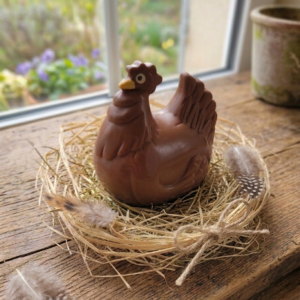 Moulage en chocolat Poule Dindon sur un nid sur une table en bois