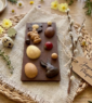 Tablette de chocolat de Pâques décorée de petits lapins, d'œufs et de fleurs en chocolat sur une table en bois
